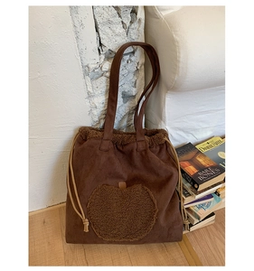Detail of coffee suede tote bag featuring brown fleece apple patch and soft drawstring