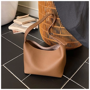Close-up of brown lychee grain leather tote with adjustable silver buckle strap