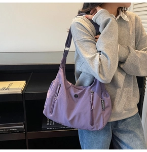 Gros plan d'un sac bandoulière en nylon violet résistant à l'eau avec poches zippées