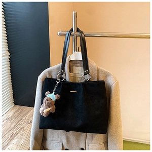 Detail of black velvet tote bag with diamond quilted texture and cute bear charm