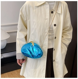 Blue metallic pebble clutch bag with gold chain shown on beige trench coat for dinner