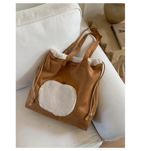 Detailed view of brown suede tote bag with white plush apple patch and fleece trim detail