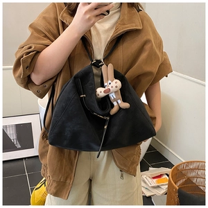 Detail view of a black soft shoulder bag with a cute brown plush rabbit pendant