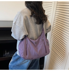 Vue détaillée d'un grand sac bandoulière violet en nylon porté par un mannequin