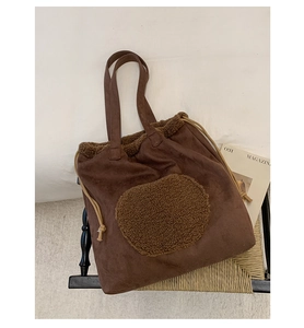 Detail of drawstring tote bag with brown faux shearling patch and suede texture