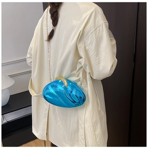 Detail of blue wavy shell evening bag with gold clasp on white coat background
