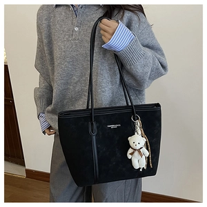 Detail of black matte tote bag featuring Fashion & Bags logo and plush bear charm