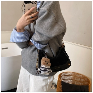 Detail of black vintage shoulder bag with suede textures and a cute teddy bear charm