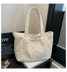 Vue détaillée du sac fourre-tout en nylon crème avec poche à cordon et compartiments
