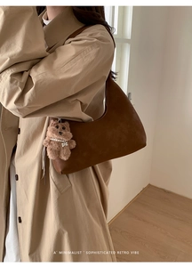 Bolso hobo marrón vintage de ante sintético con colgante de osito sobre un abrigo