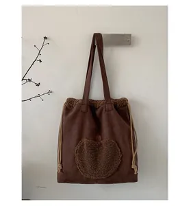Detail view of brown faux suede tote bag with coffee plush apple patch and drawstring sides