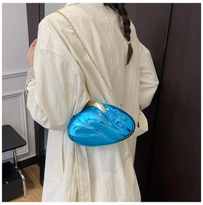Detail of a shiny blue acrylic evening bag with a gold chain strap and metallic clasp