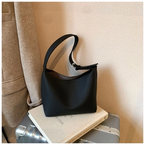 Detail view of black pebble leather tote bag with silver buckle on minimalist background