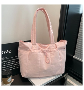 Détail du sac cabas matelassé rose clair avec coutures verticales et poche avant à cordon