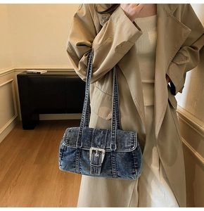 Détail du sac Boston en jean délavé avec grande boucle métallique et doubles bandoulières