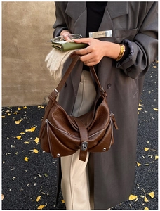 Detail of dark brown lychee leather tote bag with silver zippers and buckle accents