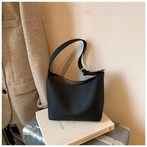 Detail of black lychee texture leather tote with adjustable strap and silver metal buckles