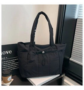 Détail du cabas en nylon noir avec poche avant à cordon et compartiments latéraux