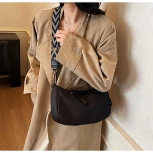 Detail of minimalist black crescent bag with wide geometric patterned shoulder strap