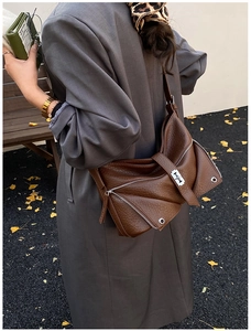 Close-up of brown lychee grain leather shoulder bag with unique geometric stitching detail