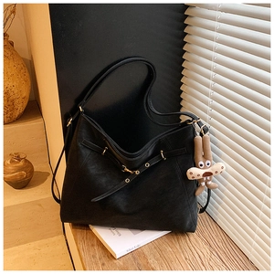 Detail of black tote bag featuring matte leather texture and cute brown bunny charm