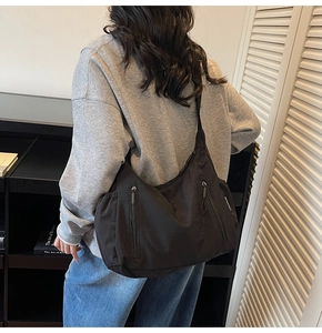 Gros plan d'un sac bandoulière en nylon noir avec étiquette de marque et poche zippée