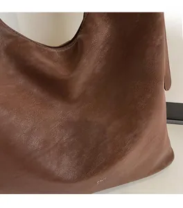 Close-up of brown litchi pattern leather texture and brand logo on a shoulder bag