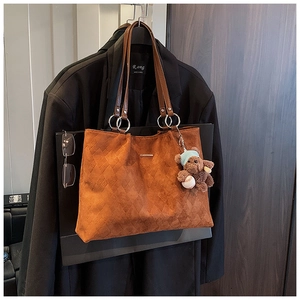 Close-up of caramel suede tote bag with diamond quilting and ring handle detail