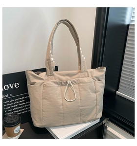 Détail d'un grand sac cabas matelassé beige avec cordons de serrage sur des livres