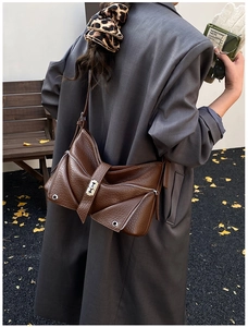 Close-up of brown litchi textured shoulder bag with decorative zippers and metal buckles