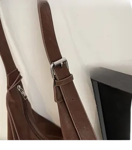 Close-up of brown pebbled leather texture with silver adjustable metal buckle and zipper