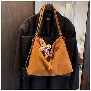 Brown faux leather tote bag with plush charm hanging on a black blazer jacket