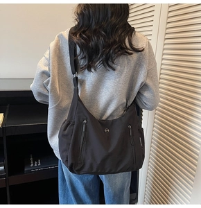 Détail d'un grand sac bandoulière en nylon avec fermetures éclair verticales et logo
