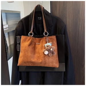 Detail of brown tote bag with quilted texture, faux fur surface and bear charm