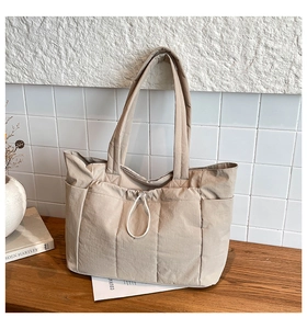 Détail d'un sac cabas en nylon matelassé beige avec poche à cordon sur bois