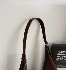 Detail of the wide, comfortable leather shoulder strap on a brown minimalist tote bag