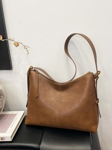 Brown vintage leather hobo bag with adjustable strap and tassel detail shown in a minimalist setting