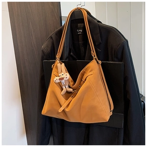 Detail of caramel faux leather tote bag with geometric stitching and cute rabbit pendant