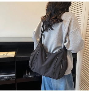 Vue latérale d'un grand sac hobo en nylon noir imperméable porté par un mannequin