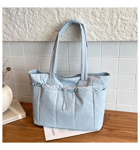 Détail du sac cabas matelassé bleu clair avec plusieurs poches et cordon de serrage