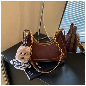 Brown suede shoulder bag featuring a chunky gold chain and cute plush dog charm detail