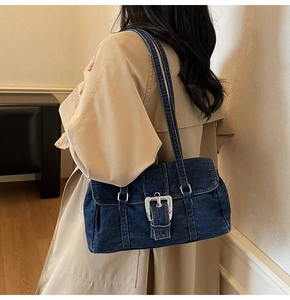 Détail du sac Boston en denim bleu vintage avec boucle argentée porté par un mannequin