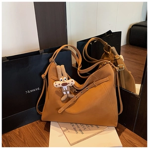 Detail view of the brown leather tote bag texture with rabbit charm and metal eyelet strap