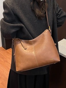 Brown large capacity leather tote bag with white contrast stitching and shoulder straps