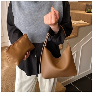 Close-up of caramel leather tote bag set with matching pouch on indoor stairs