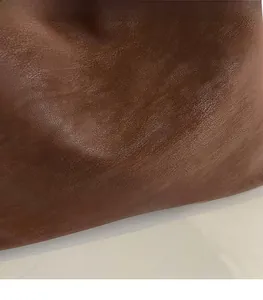 Macro detail of brown lychee grain leather underarm bag with embossed text logo