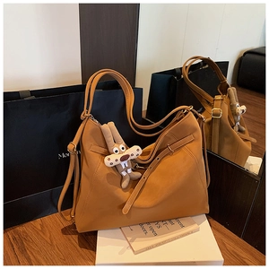 Detail view of ginger yellow leather tote bag with a cute plush rabbit charm and strap