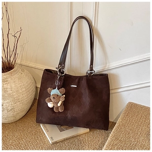 Detail of dark coffee suede tote bag with woven texture and cute bear charm pendant