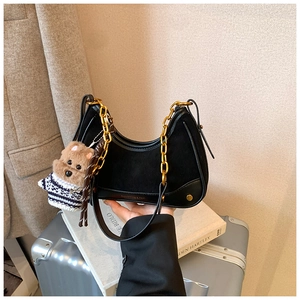 Detail of vintage black patchwork handbag with gold chain strap and cute bear charm pendant