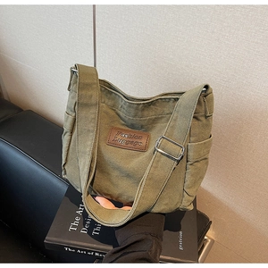 Detail of olive green canvas tote bag with brown leather label and silver buckle